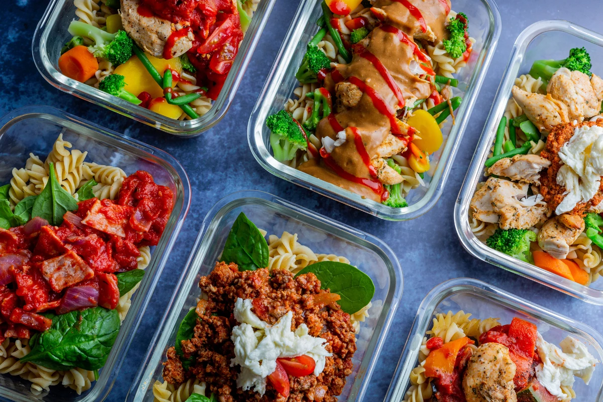 Variety of colorful prepped meal containers with pasta