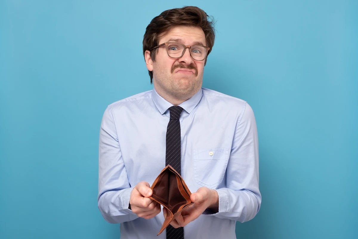 Business man with goofy face and glasses against blue background showing his empty wallet.