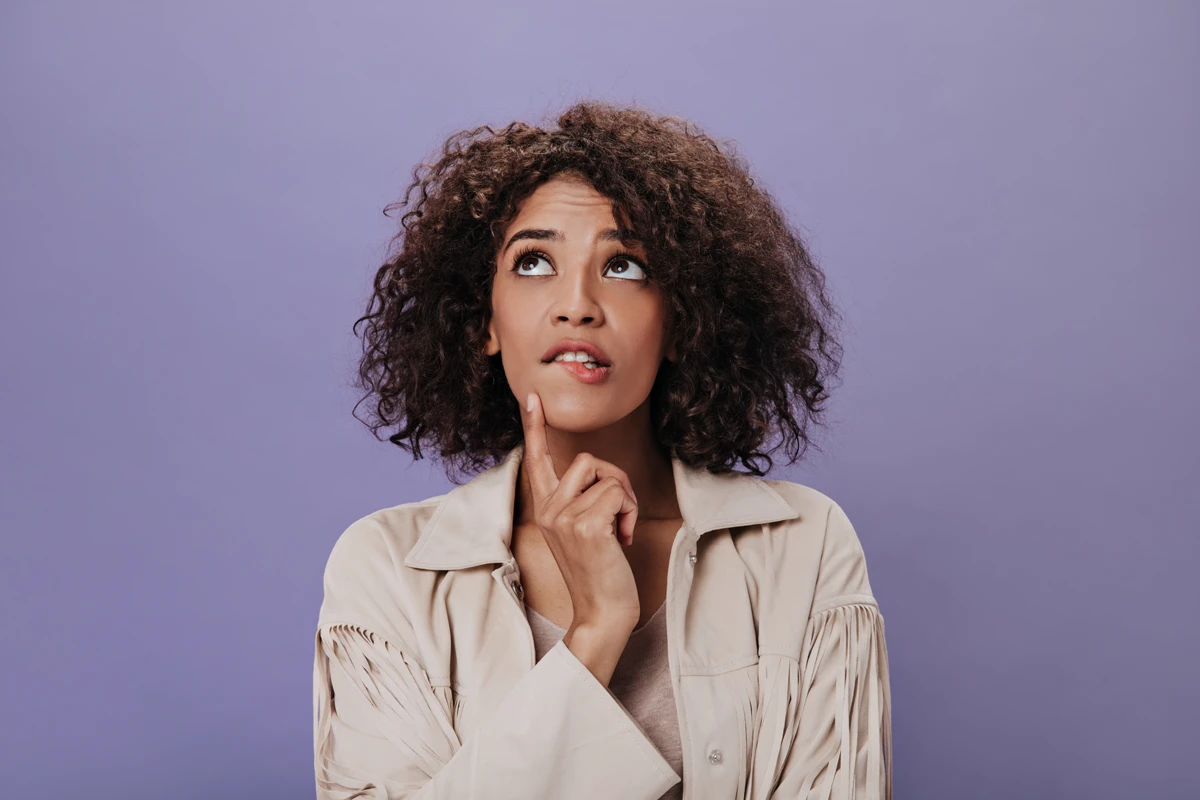 Thoughtful woman pondering with finger on chin.