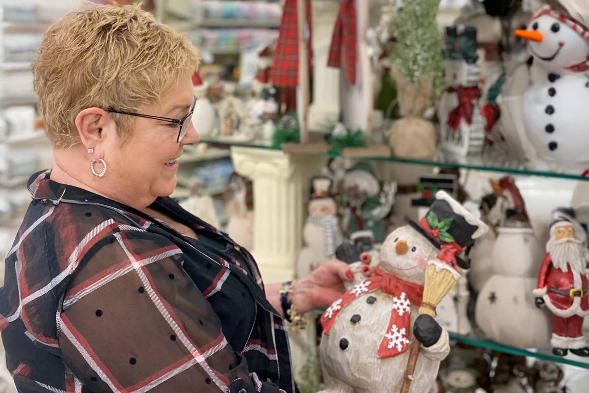 Woman admiring snowman figurine in store.