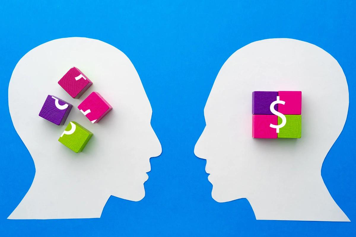 Two heads with colorful blocks and symbols representing someone who knows about money and someone who doesn’t.