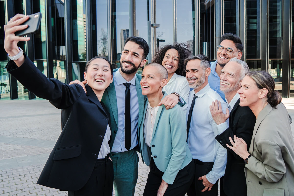 Diverse group of professionals taking selfie outdoors.