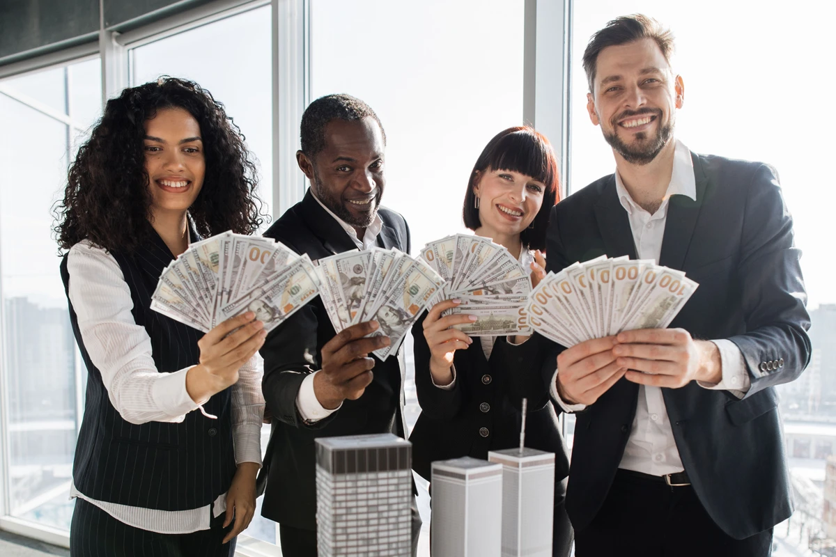 Four professionals holding money with joy in office