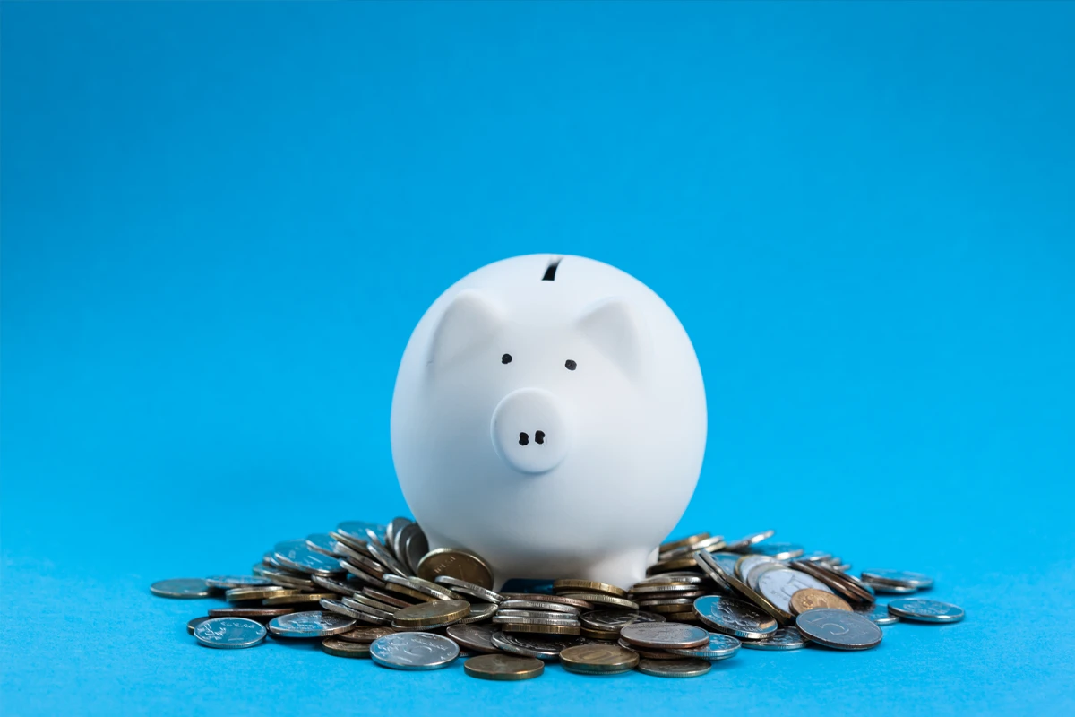 White piggy bank on coins, blue background