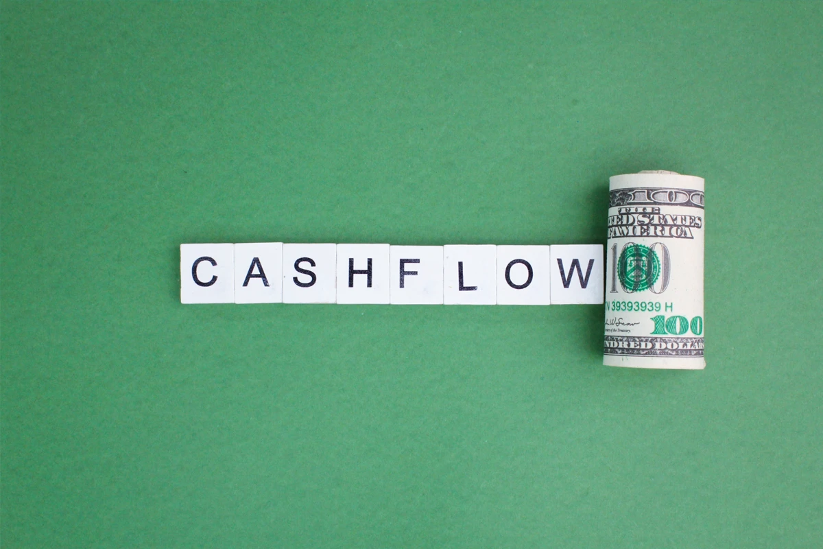 Scrabble tiles spelling 'CASHFLOW' next to money roll