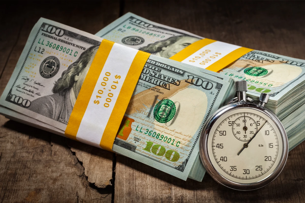 Stack of US dollar bills tied with stopwatch