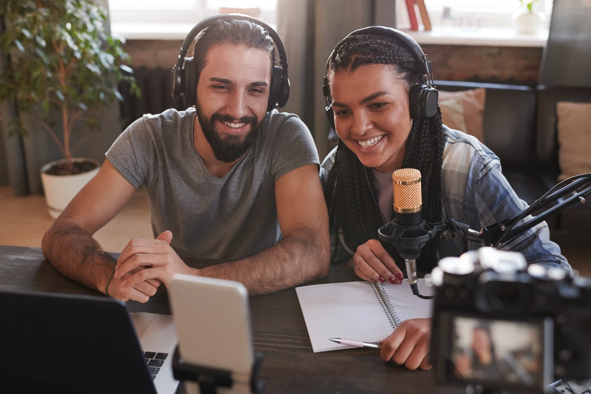 Podcast hosts recording episode with microphone and laptop