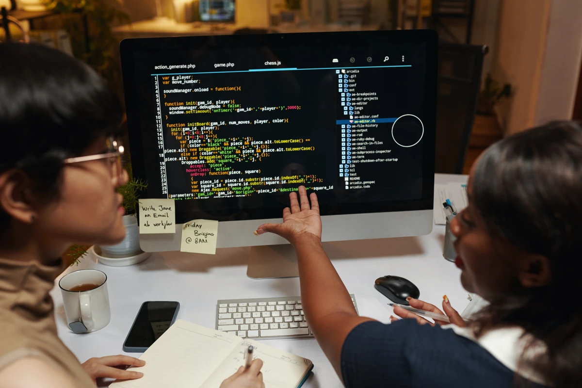 Two programmers discussing code on computer screen