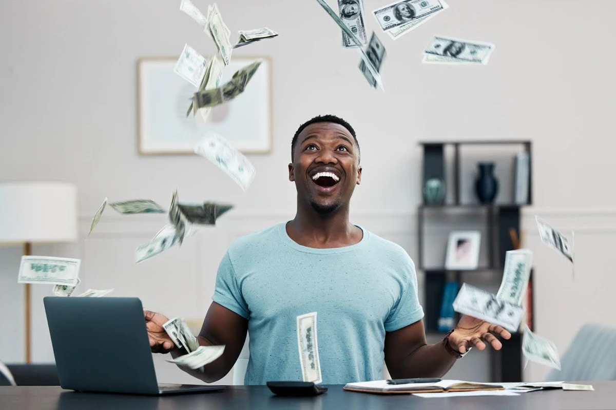 Man excited as money flies around him indoors