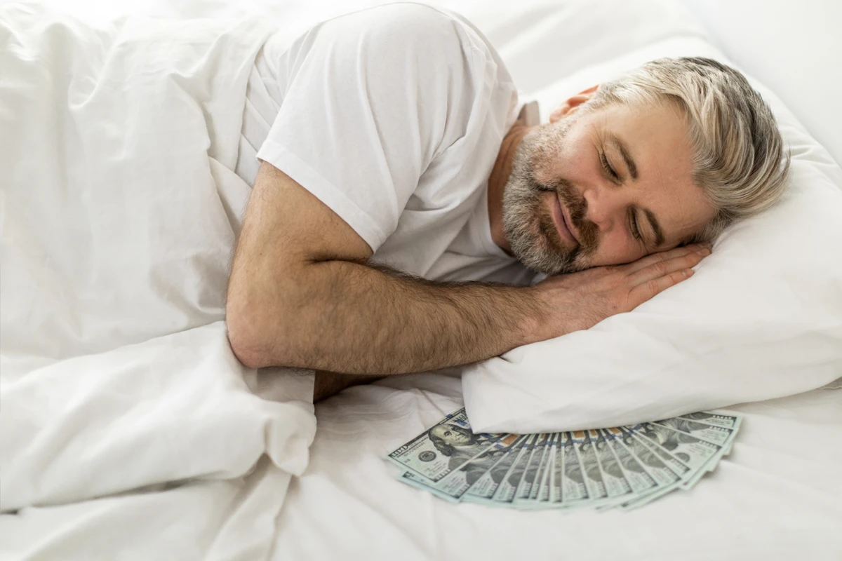 Man sleeping peacefully beside money on bed