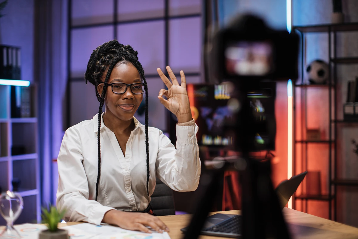 Woman recording video in studio, showing peace sign