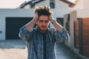 Man looking distressed holding head outdoors