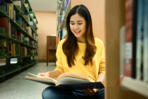 Young woman reading book in library