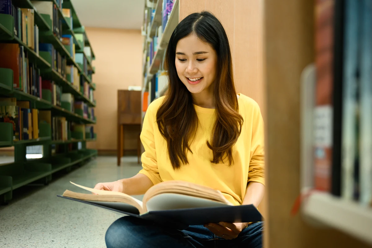 Young woman reading book in library