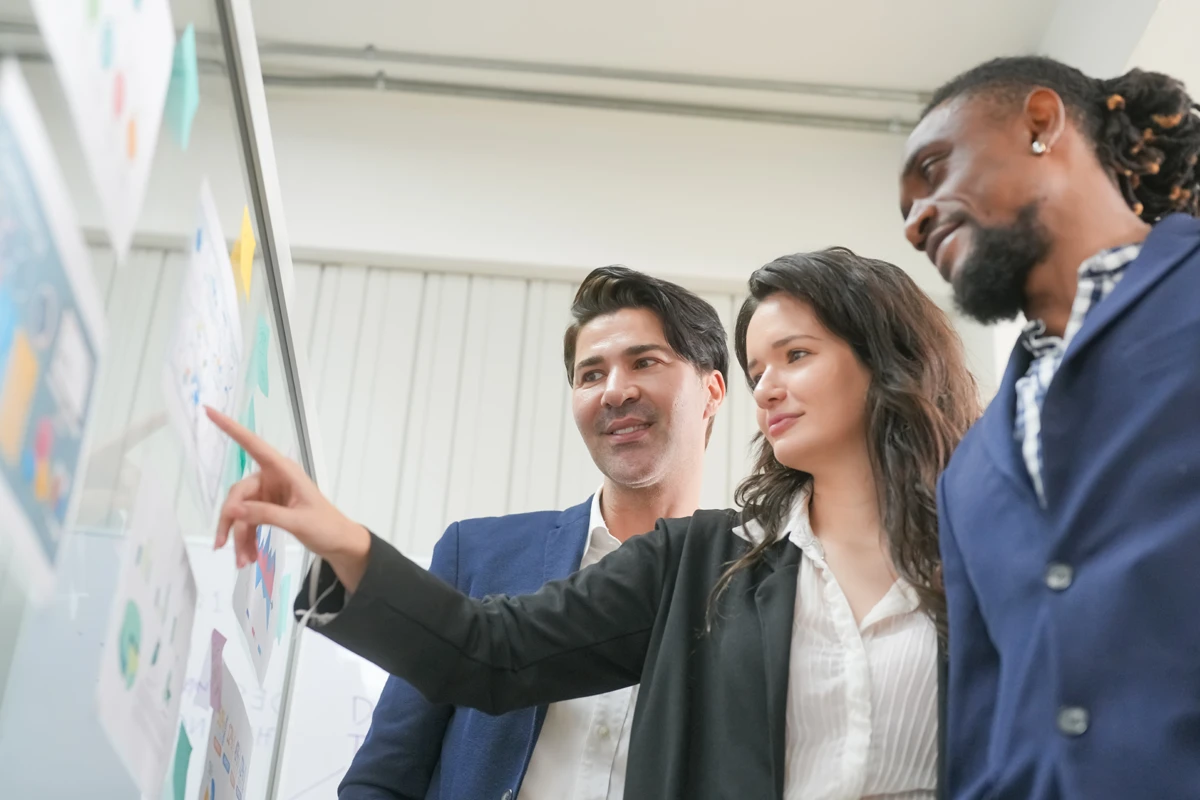 Three professionals discussing over a whiteboard in office