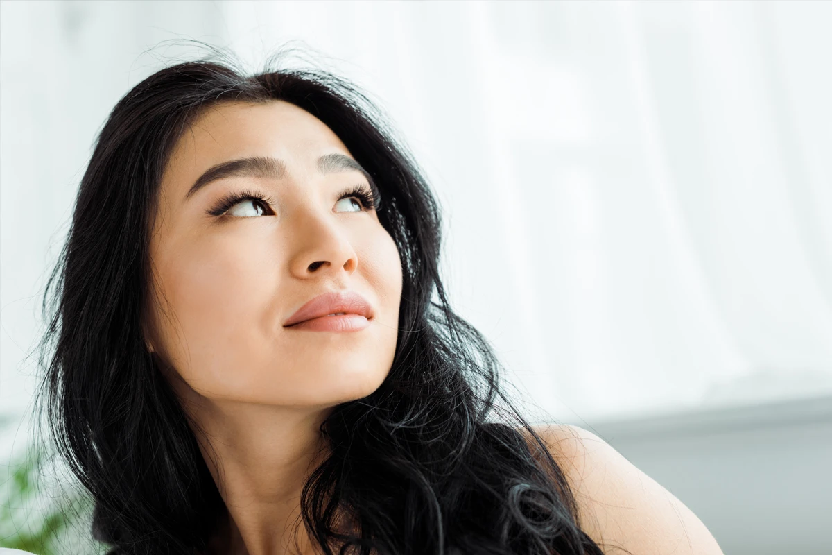 Asian woman looking up thoughtfully indoors
