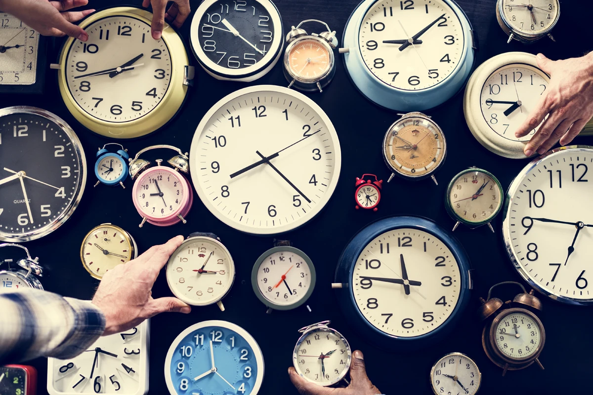 Variety of clocks on a table with hands adjusting times