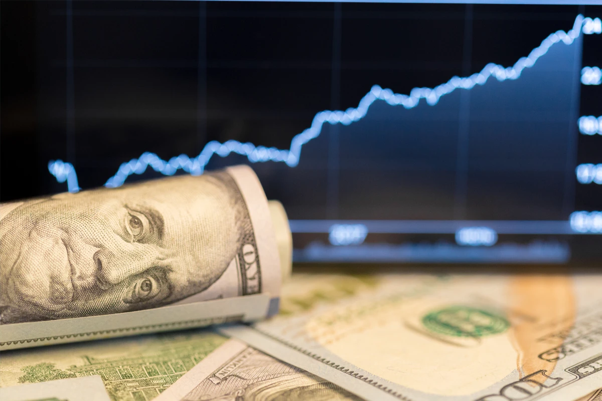 U.S. currency with stock market graph in background