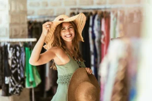 Happy woman trying on straw hat in boutique