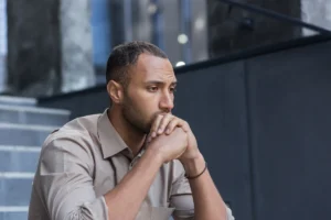 Thoughtful man sitting outdoors in urban setting