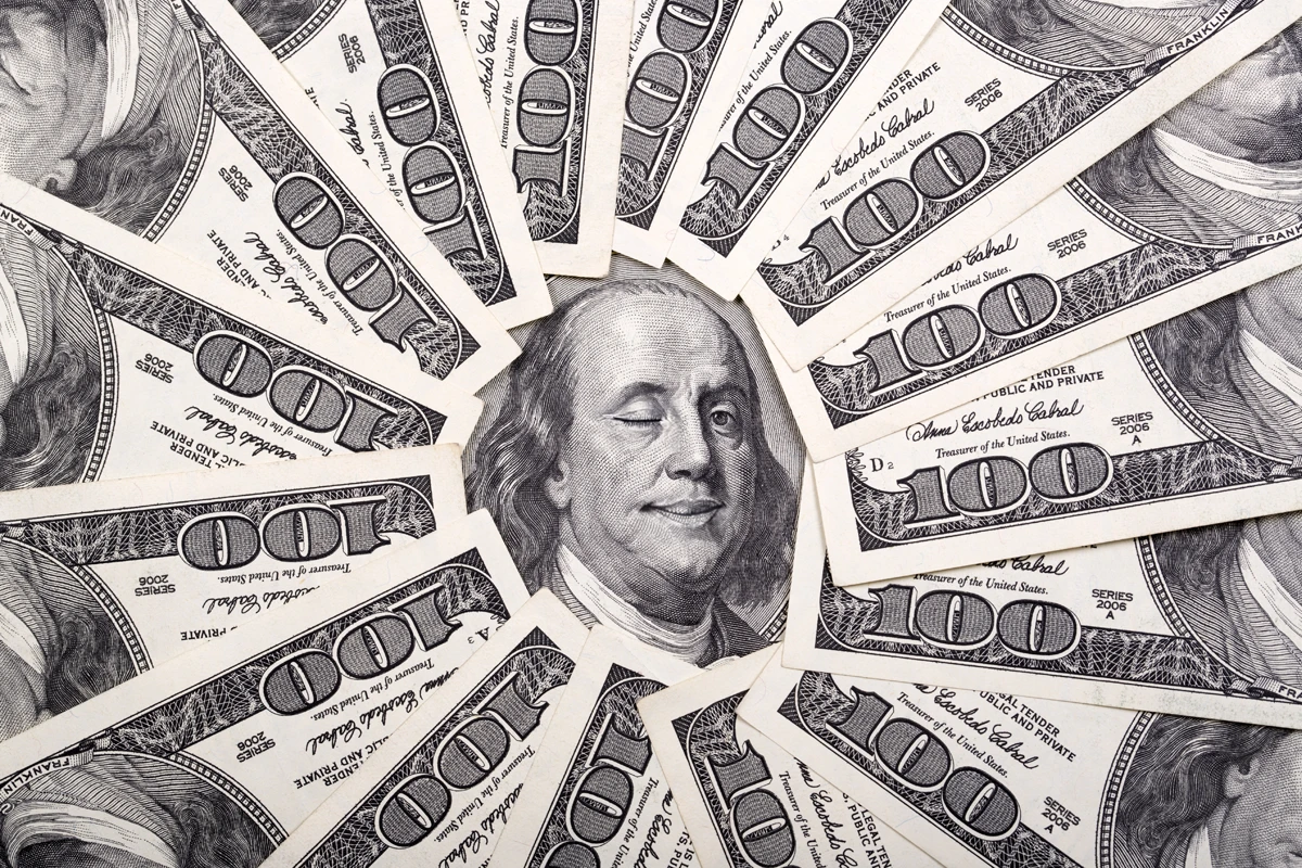 Scattered U.S. hundred dollar bills featuring Benjamin Franklin