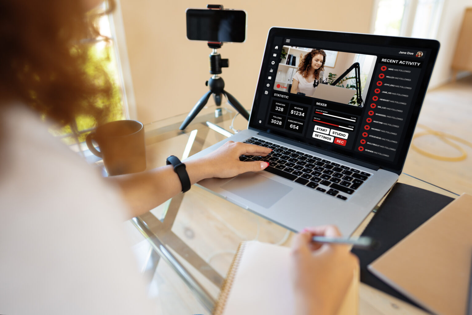 Woman livestreaming on laptop with smartphone as webcam