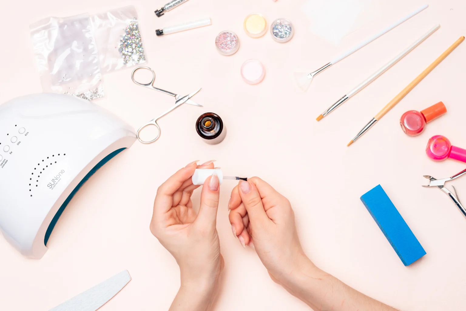 Person applying nail polish with manicure tools around