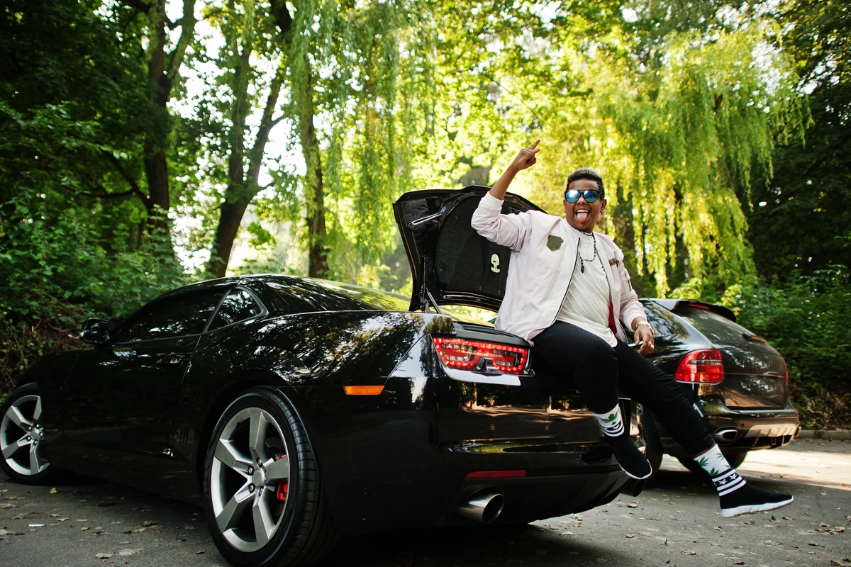 Man sitting in car trunk waving enthusiastically