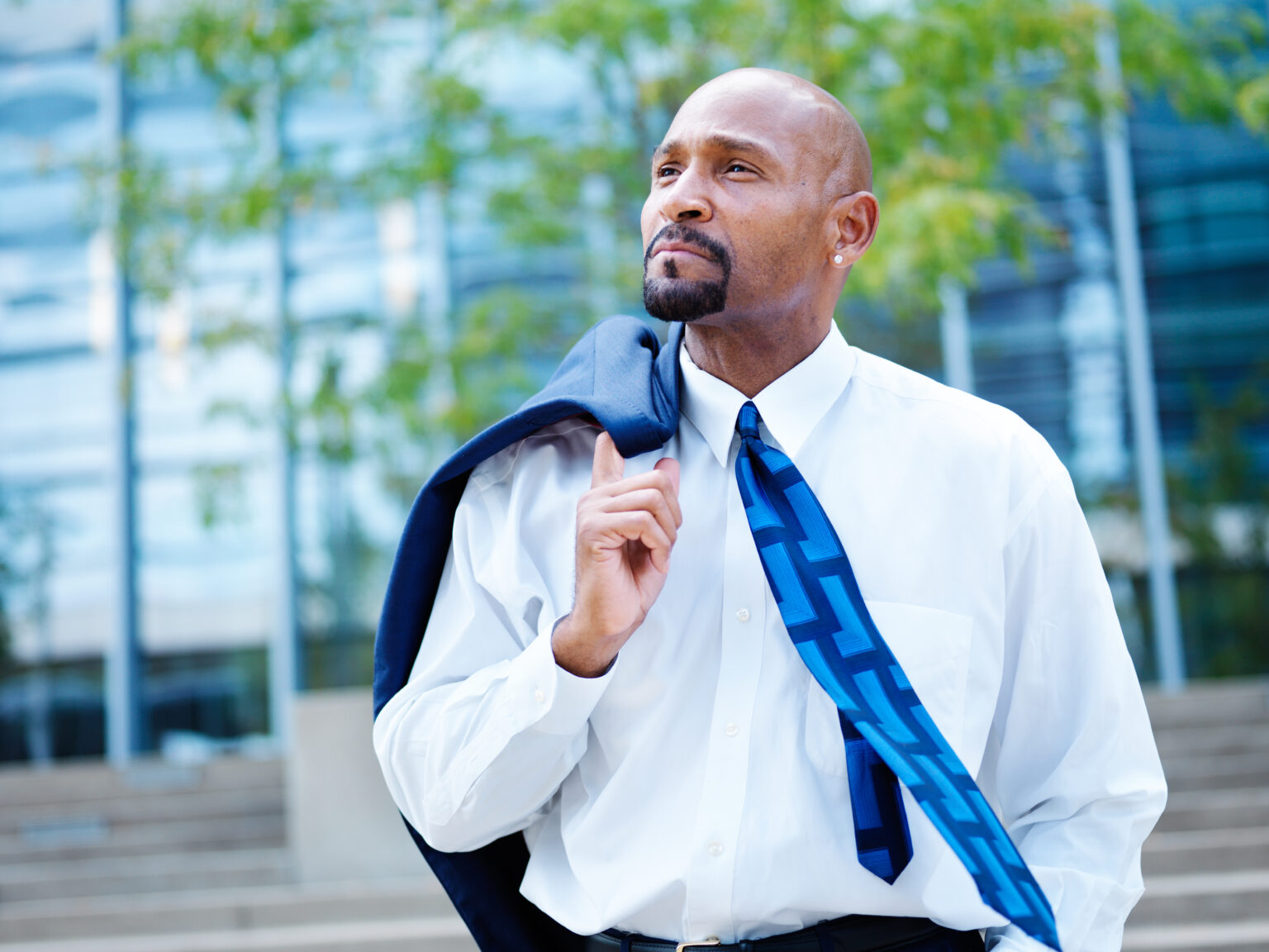 Confident businessman outdoors with coat over shoulder