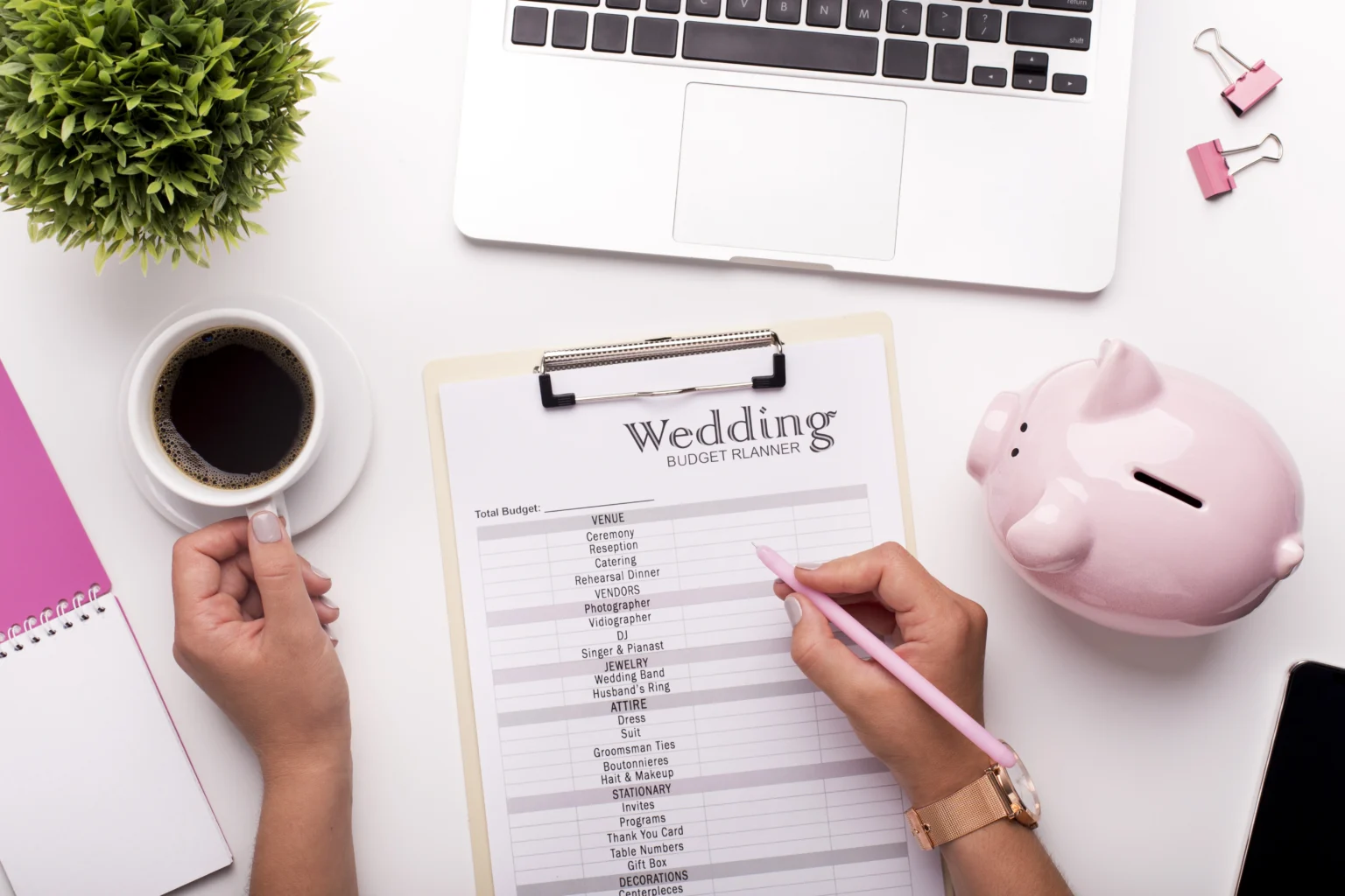 Person planning budget with wedding planner and laptop