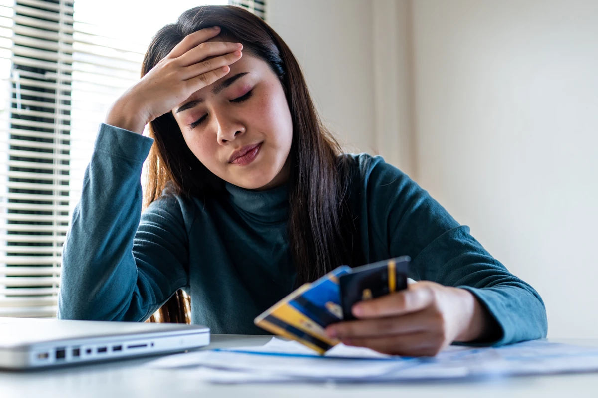 Worried woman holding credit cards with financial documents