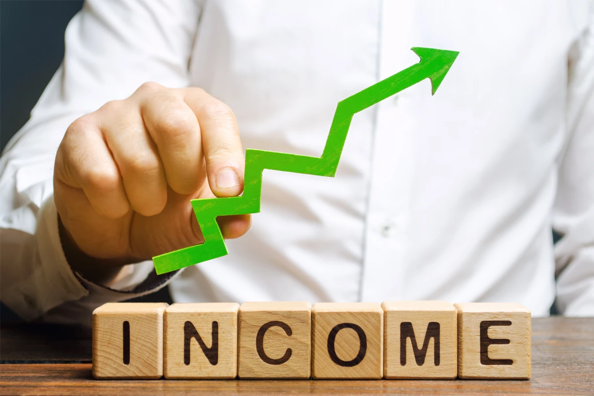 Person pointing to rising income graph on blocks