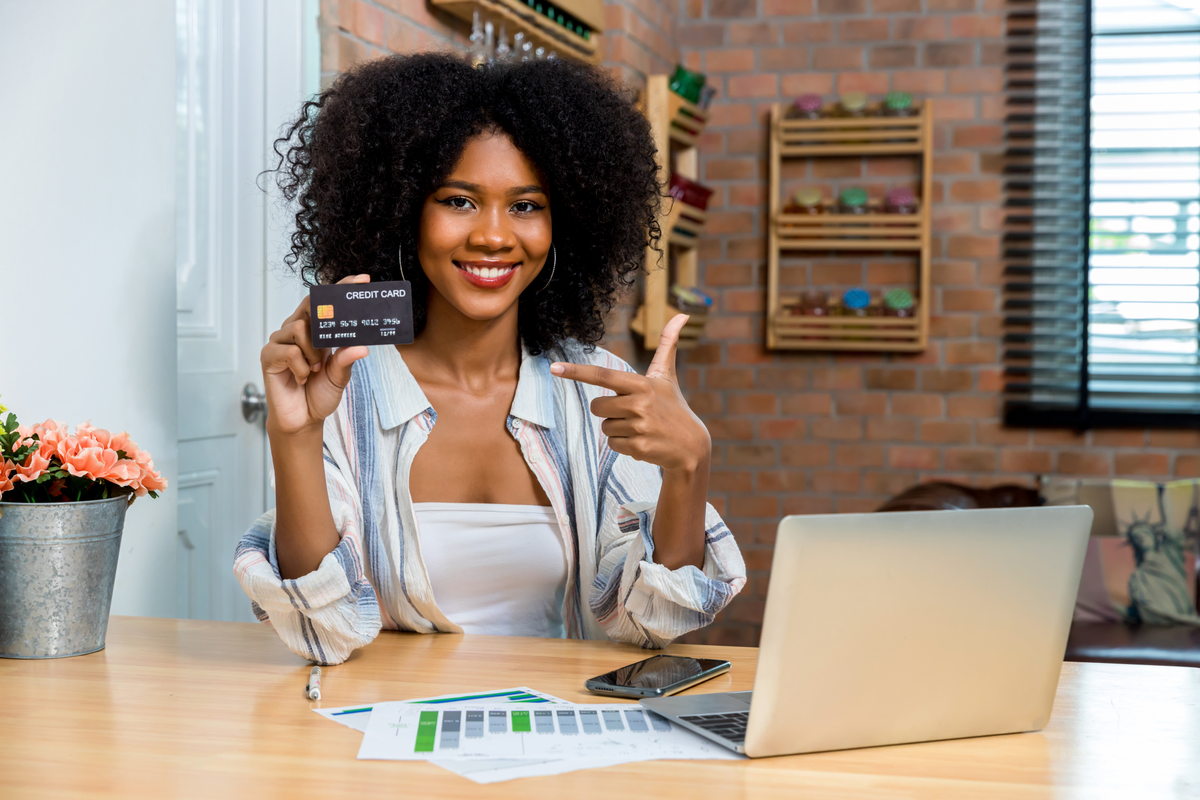 Woman showing credit card at desk with laptop
