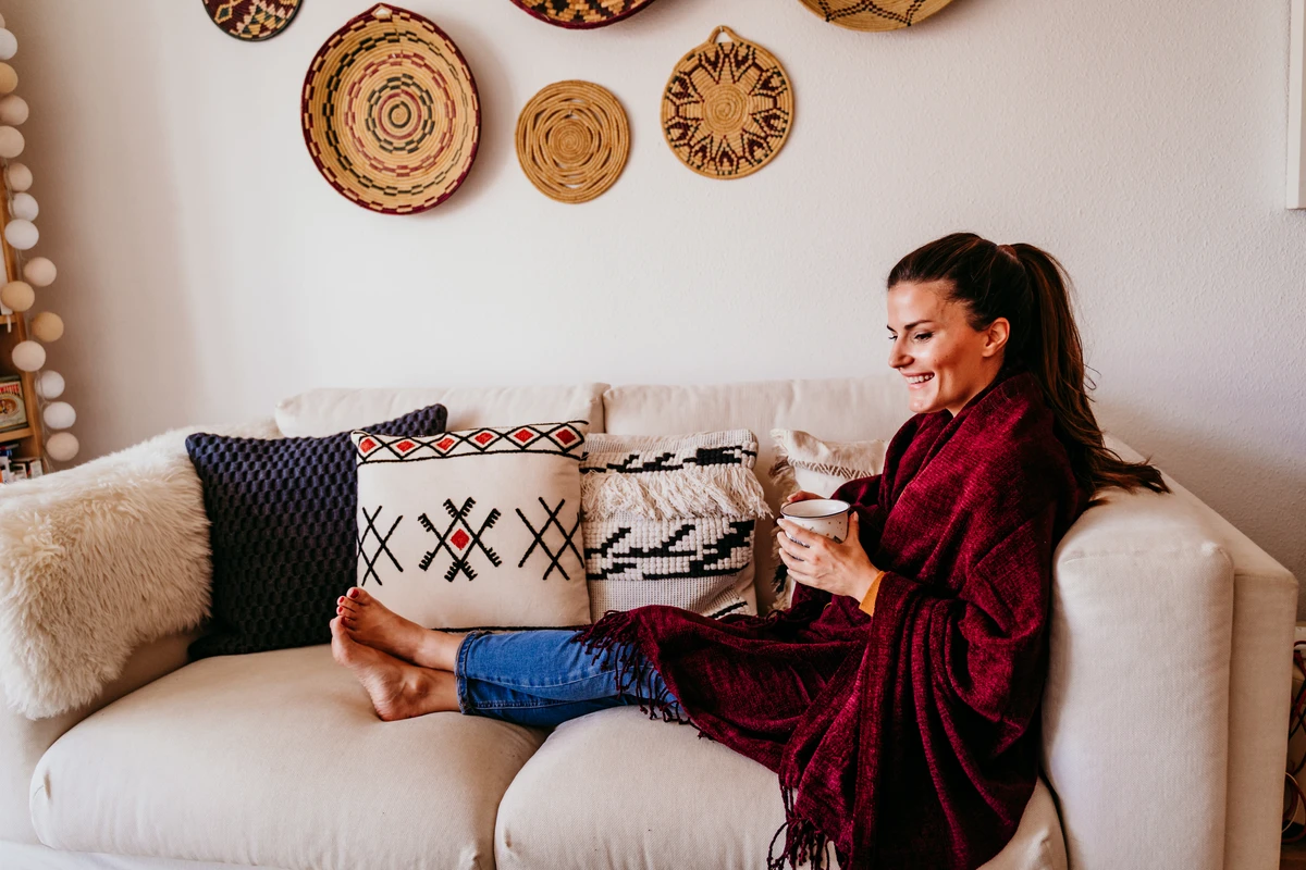 Woman relaxing on couch with coffee and decorative pillows