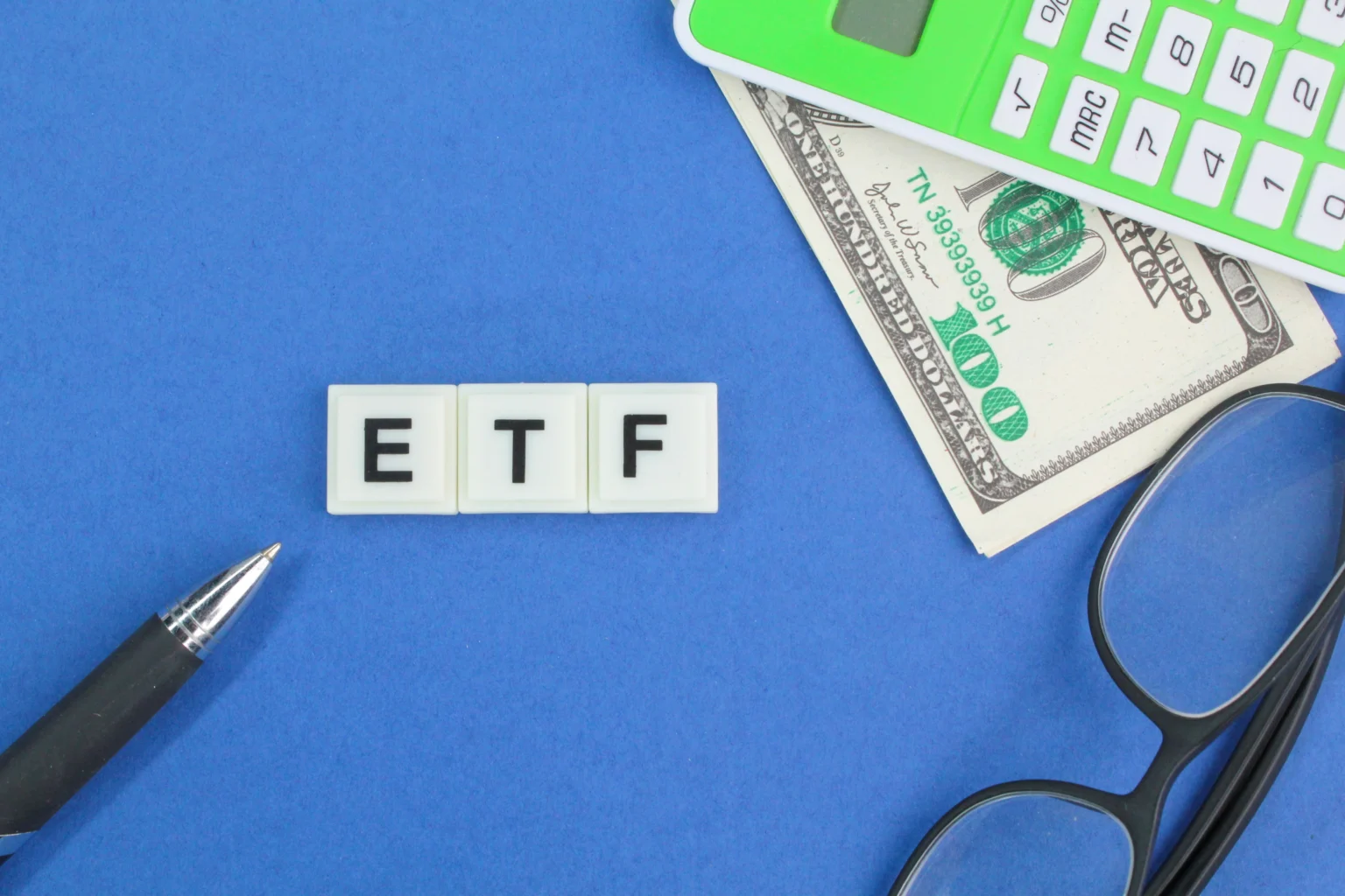 ETF concept with calculator, money, and glasses on blue
