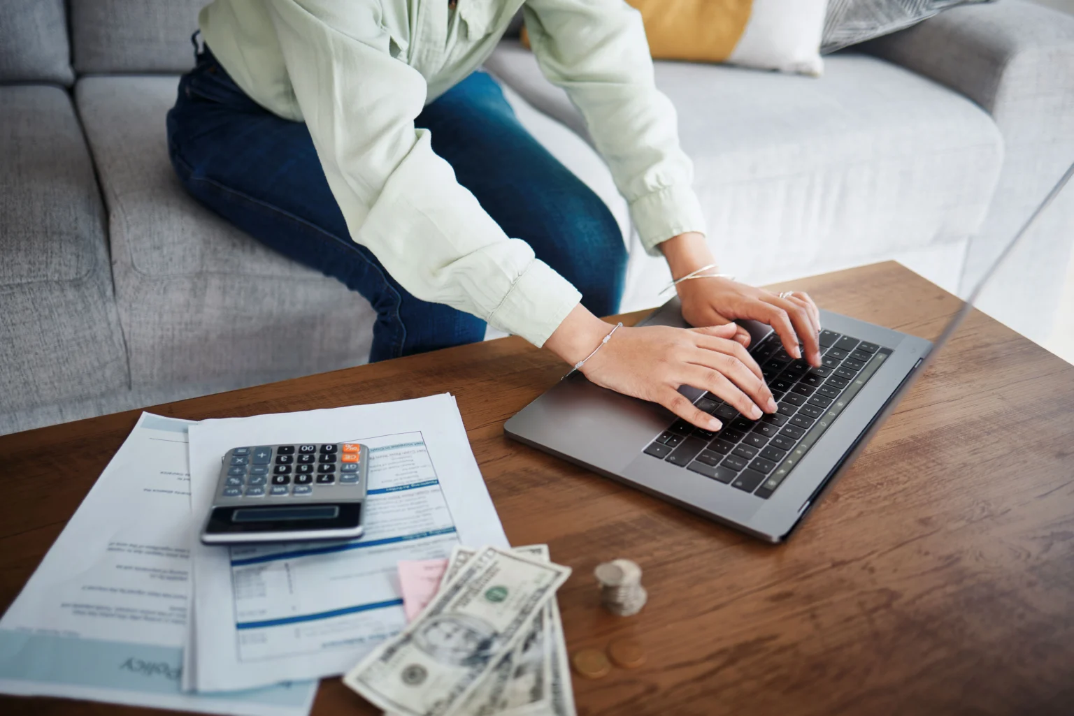 Person budgeting finances on laptop with calculator nearby