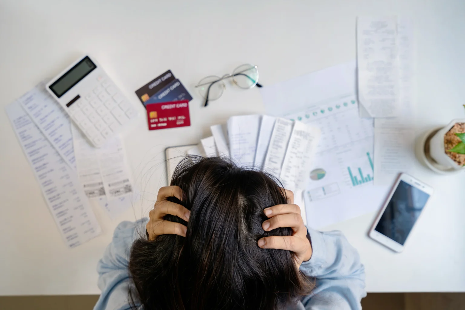 Person stressed over financial documents and calculator