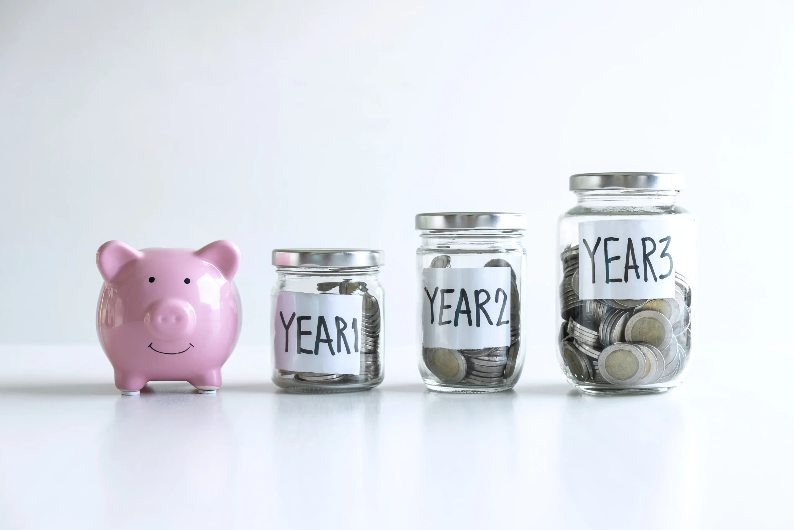 Piggy bank and jars labeled years with coins inside
