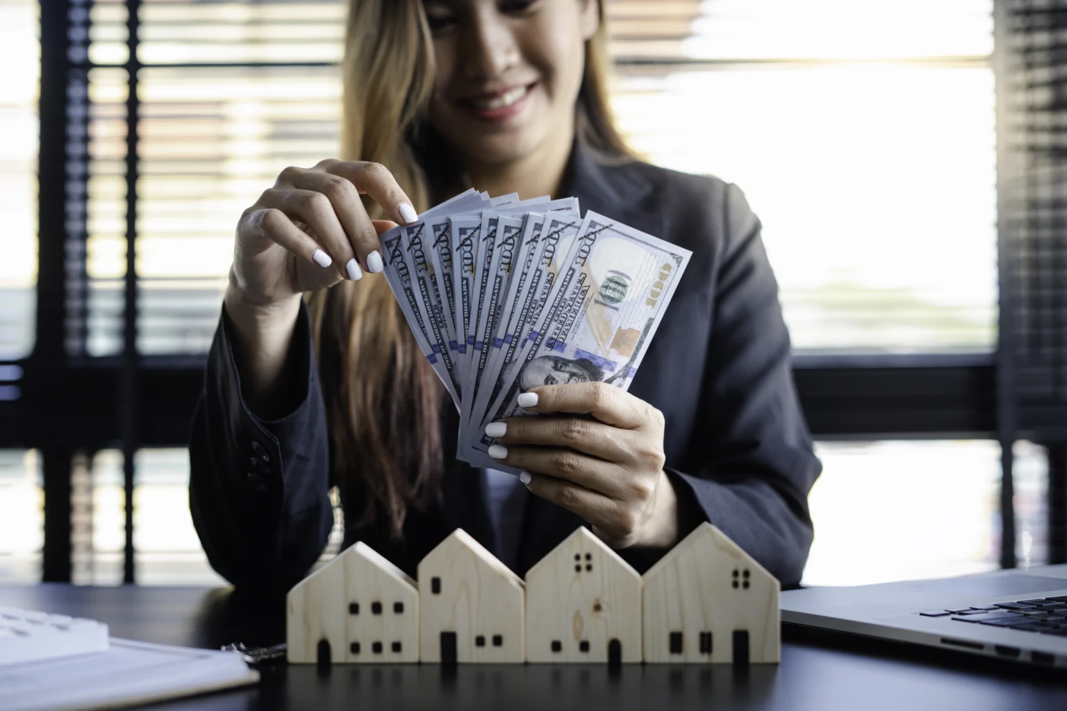 Woman counting money near wooden house models