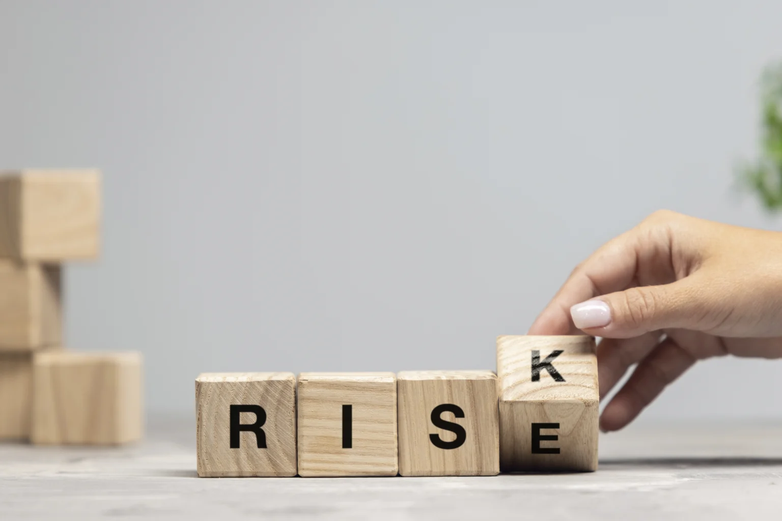 Hand arranging wooden blocks spelling RISE