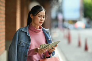 Woman counting money after shopping outdoors