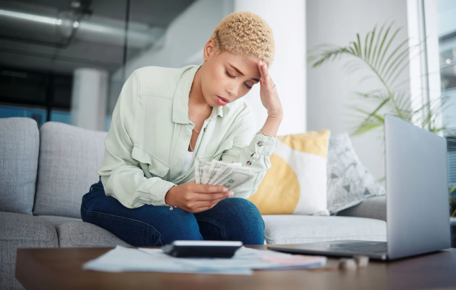 Worried woman counting money with laptop and documents