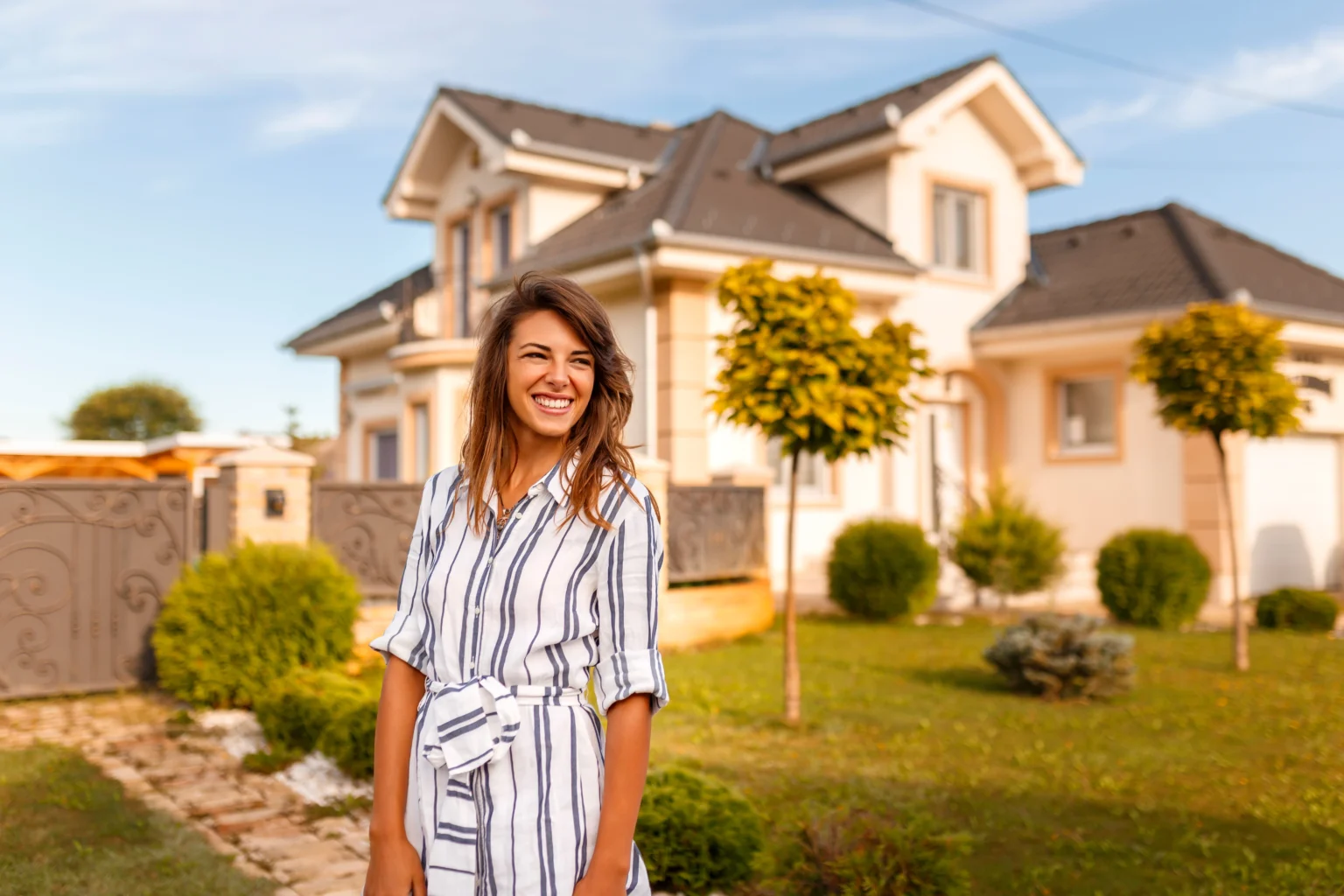 Smiling woman standing in front of upscale house
