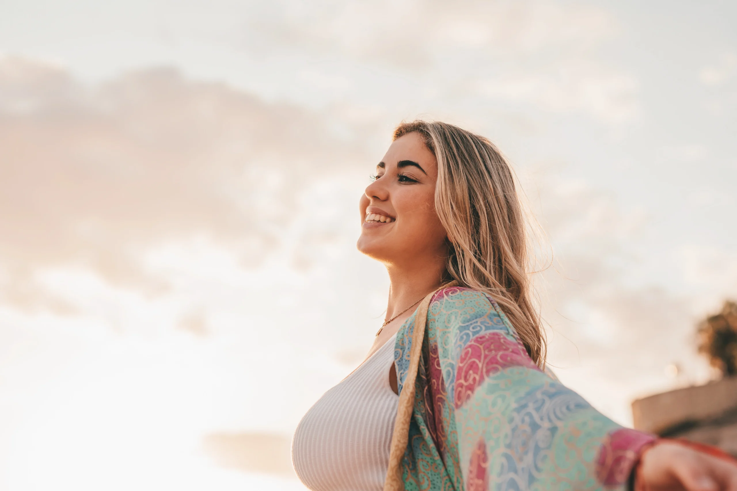 Joyful woman in sunlight wearing colorful outfit