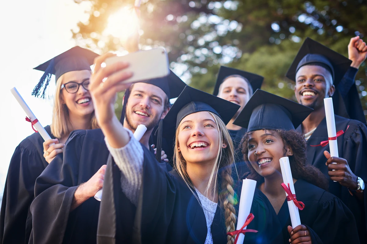 Graduates taking selfie with diplomas at commencement