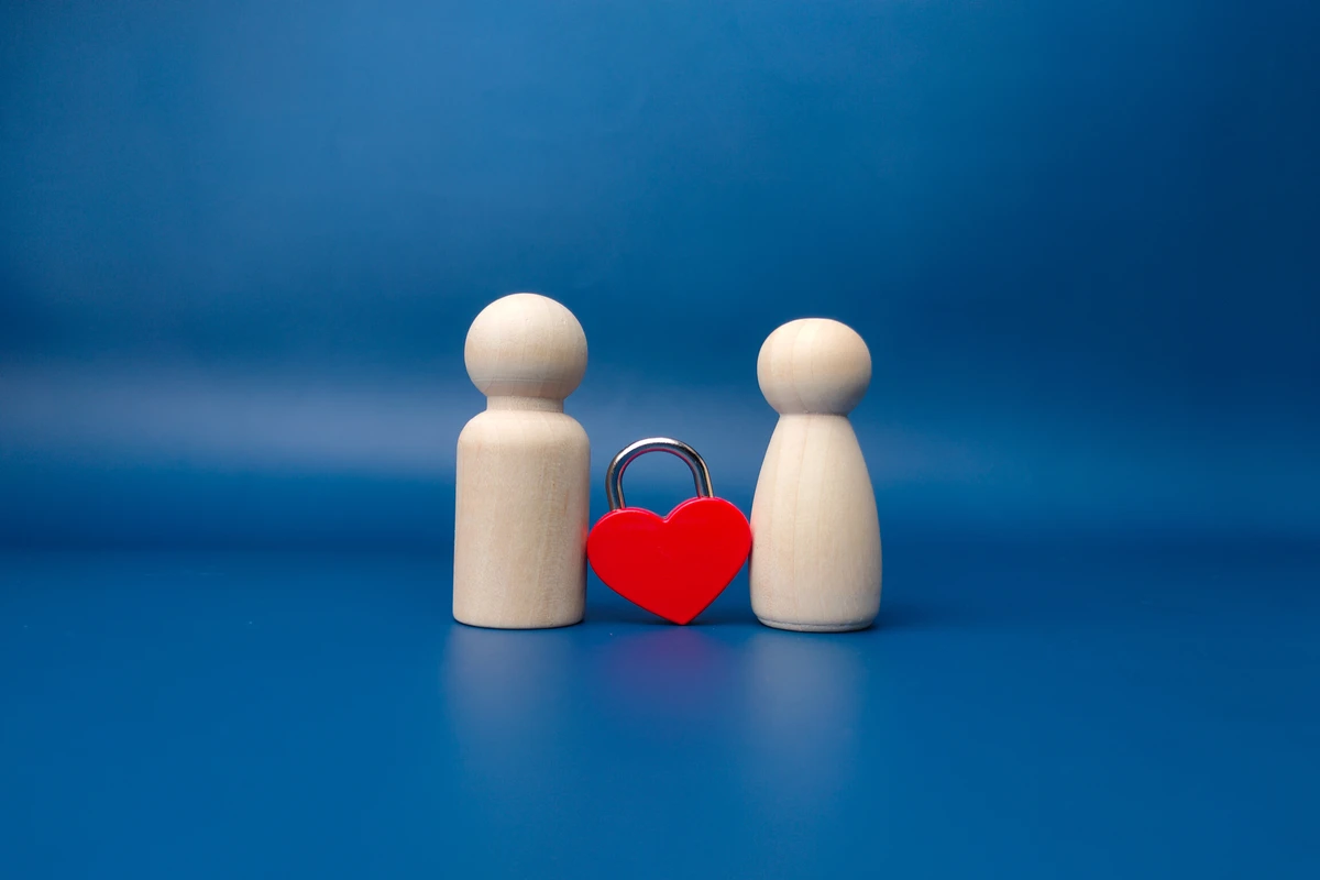 Wooden figures with heart-shaped lock on blue