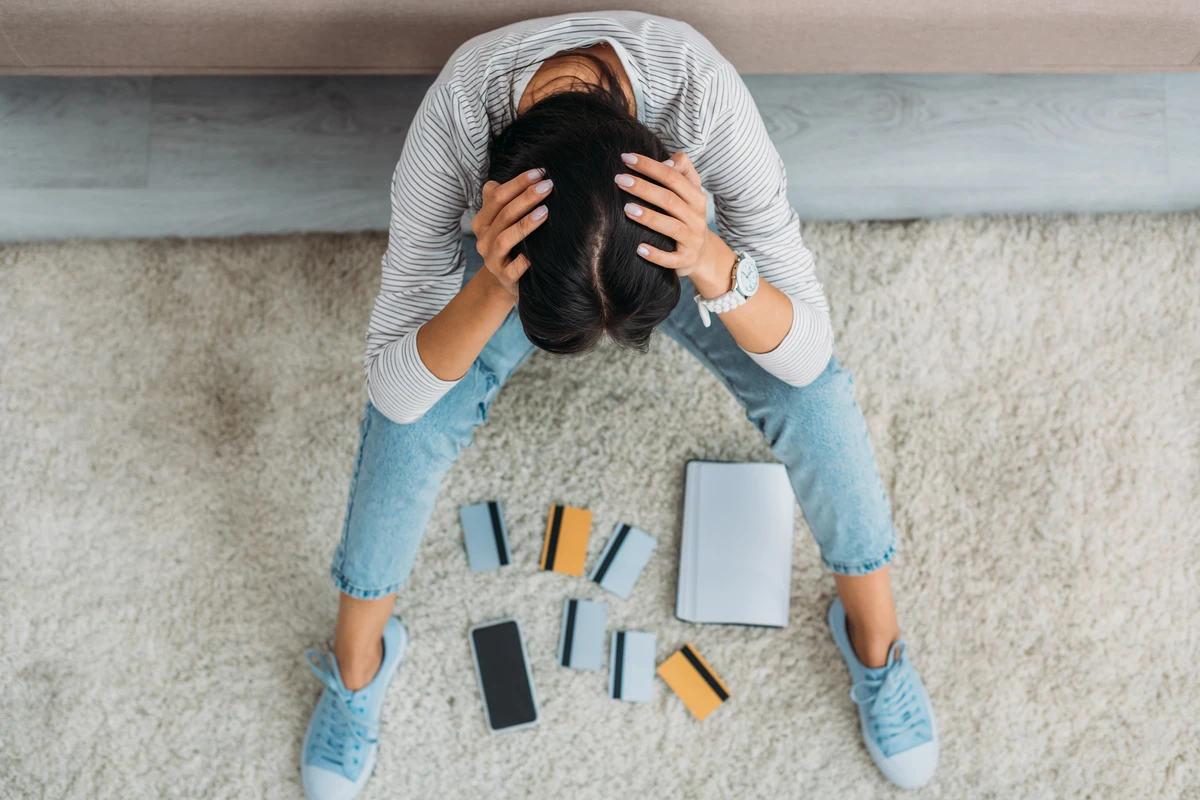 Overwhelmed woman sitting among scattered electronic devices
