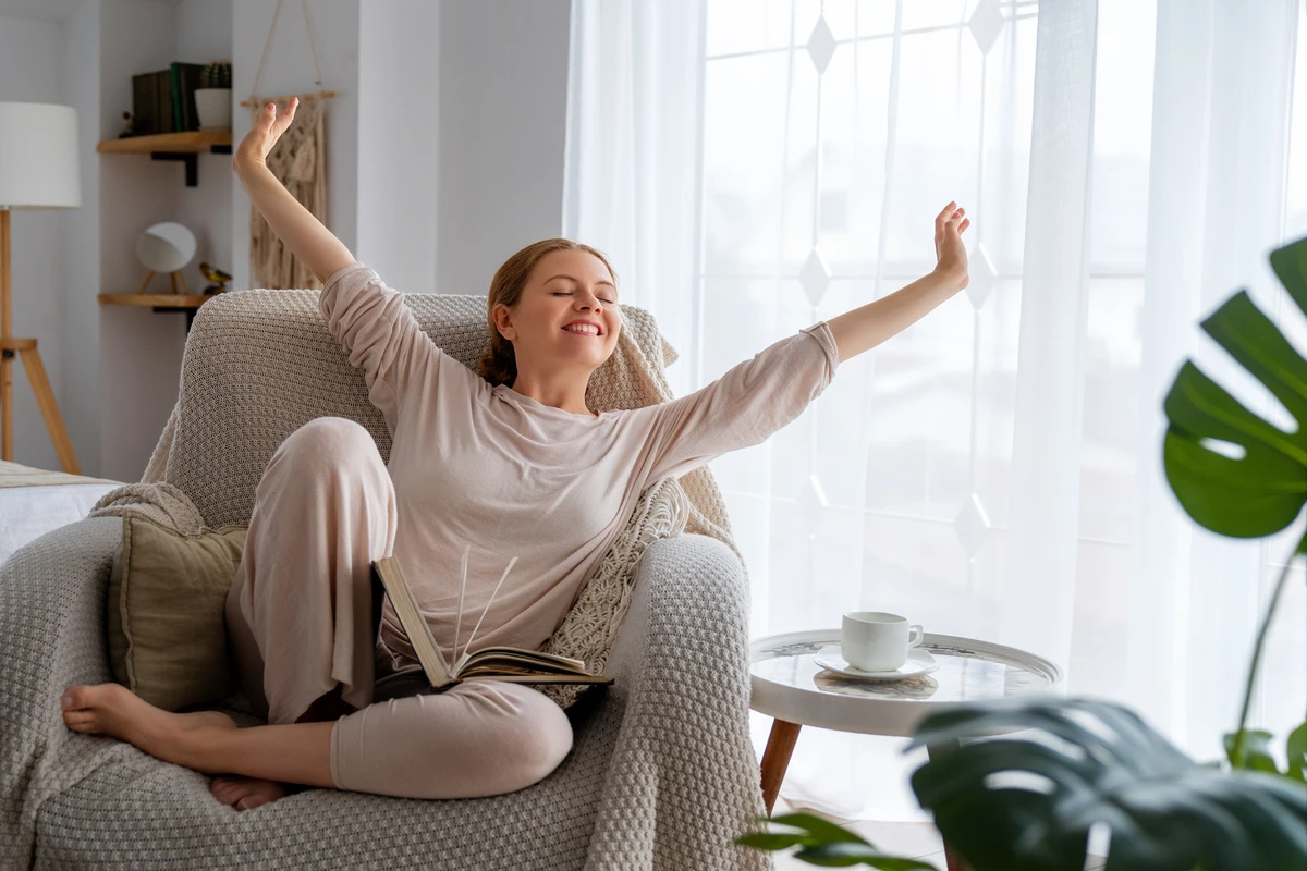 Woman relaxing in chair, stretching with book and coffee