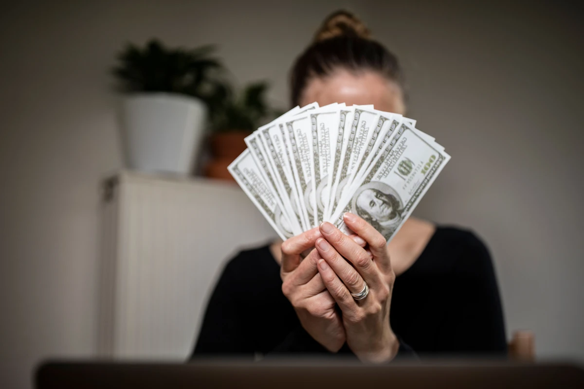 Woman holding fan of US dollar bills