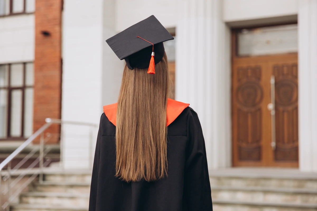 Graduate in cap facing university building